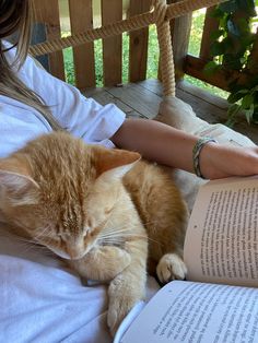 an orange and white cat laying on top of a woman's lap while reading a book