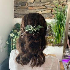 a woman sitting in front of a mirror wearing a hair comb with flowers on it