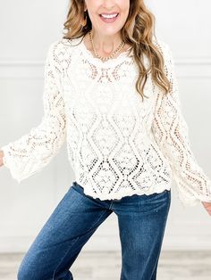 a woman in jeans and a white sweater posing for the camera with her hands on her hips