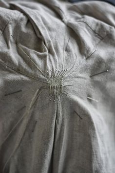 an unmade bed with silver sheets and pillows on it's headboard is seen in this close up photo