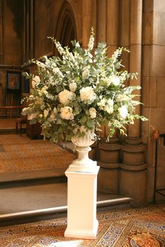 a vase filled with white flowers sitting on top of a floor next to a doorway