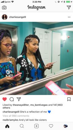 two women standing on an escalator looking at their cell phones