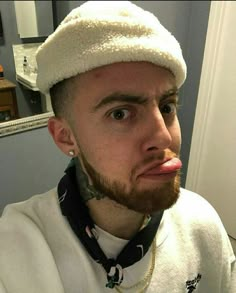 a man with a beard wearing a white hat in a bathroom next to a mirror