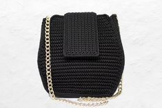 a black crocheted purse with chain hanging from it's front and shoulder