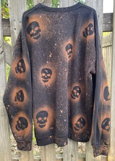 a black shirt with skulls on it hanging from a wooden fence