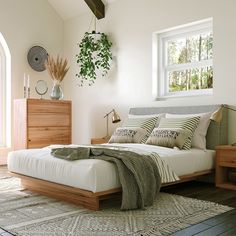 a bedroom with a bed, dresser and plant in the corner on top of it