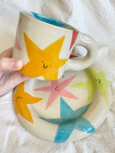 a hand holding a coffee cup and saucer on top of a white table cloth