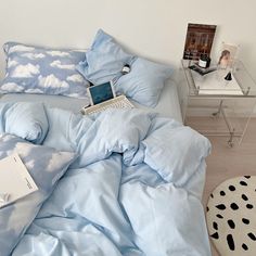 an open laptop computer sitting on top of a blue comforter in a bed room