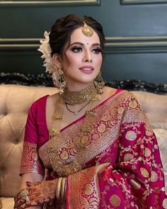 a woman in a red and gold sari sitting on a couch