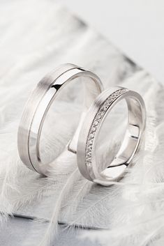 two wedding rings sitting on top of a feather