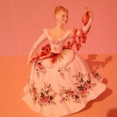 a figurine that is sitting on top of a table in front of a pink wall