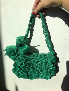 a person holding a green purse with a bow on it's handle and string