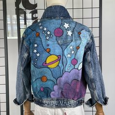 a mannequin wearing a jean jacket with an outer space theme painted on it