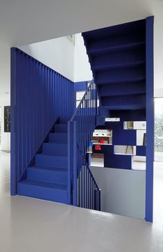 a blue stair case next to a white wall with bookshelves in the background