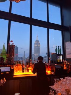 a man standing in front of a bar filled with liquor bottles and glasses next to tall buildings