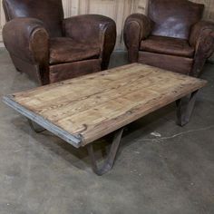 two leather chairs and a wooden table in a room