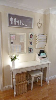 a white desk with flowers and pictures on the wall next to an entryway door