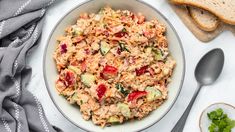 a bowl filled with tuna salad next to sliced bread