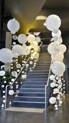 some white balloons are hanging from the stairs