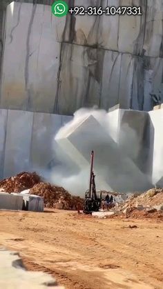 an excavator is working on the side of a large iceberg with mountains in the background