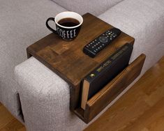 a coffee cup sitting on top of a wooden table next to a book and remote control