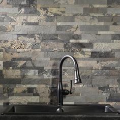 a kitchen sink sitting under a faucet in front of a wall mounted stone tile backsplash