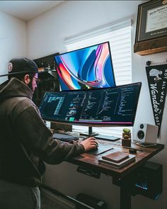 a man sitting in front of two computer monitors