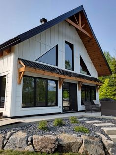 a white house with black shingles and wood trimmings on the front porch