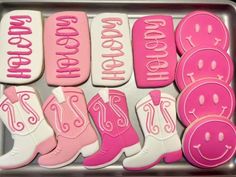 pink and white decorated cookies with cowboy boots on them are sitting in a baking pan