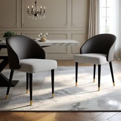 two chairs sitting in front of a table with a chandelier hanging from the ceiling