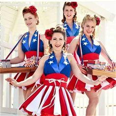 four women dressed in patriotic outfits holding trays and posing for the camera with their hands on their hips