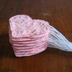 a stack of pink paper sitting on top of a wooden table next to a white string