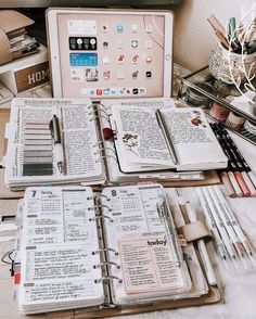 an open book sitting on top of a desk next to a laptop computer and other items