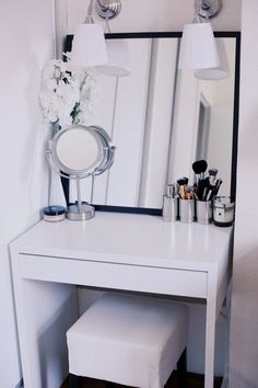 a white vanity table with a mirror and two lights above it, along with other makeup items