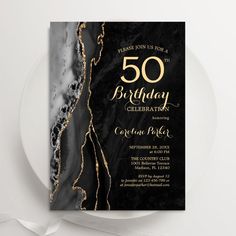 a black and gold 50th birthday party card on a plate with a white ribbon around it