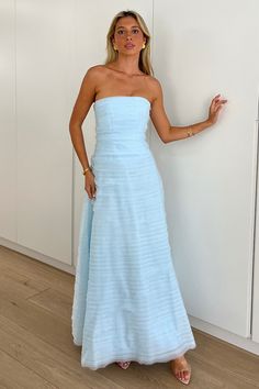 a woman in a blue dress standing next to a wall