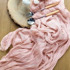 a pink cloth with spoons and utensils in it on a wooden table