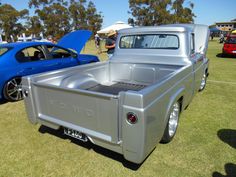 an older pickup truck is parked on the grass near other old cars at a car show