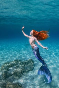 a woman with red hair is swimming in the ocean