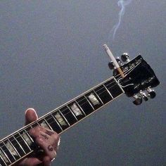 a person holding an electric guitar with a lightning bolt in the sky above them,