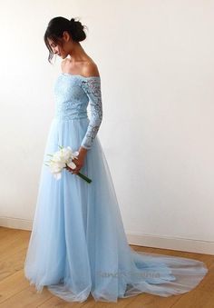 a woman in a blue dress holding a white flower and looking down at the floor