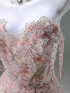 a dress with pink flowers on it and beading around the neckline is displayed