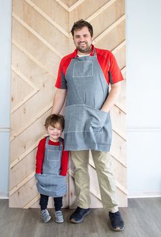 a man standing next to a little boy wearing an apron