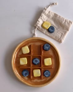 a plate with blueberries and cheese on it next to a cloth bag filled with candy