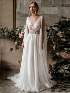 a woman in a white wedding dress standing next to flowers