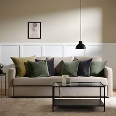 a living room with a couch, coffee table and pictures on the wall behind it