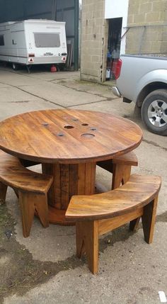 a wooden table and bench sitting in the middle of a parking lot next to a truck