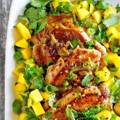 chicken and mango salad with cilantro, pineapple, and parsley on a white platter