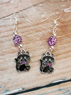 Black cat long dangly earrings, with metallic purple acrylic beads.  The metal used is silver plated and nickel free. The black cat charm is enamel charms, which have a tint of sparkly in them.  They dangle approx. 55 mm from the earlobe and are 12 mm in width.  Ideal to wear at any occasion. Trendy Cat Design Jewelry For Party, Trendy Cat Design Jewelry For Parties, Metal Cat Design Drop Earrings, Cat Design Metal Drop Earrings, Purple Beaded Earrings, Women Summer Fashion, Purple Acrylic, Purple Beaded, Jewellery For Women