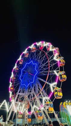 the ferris wheel is brightly lit up at night